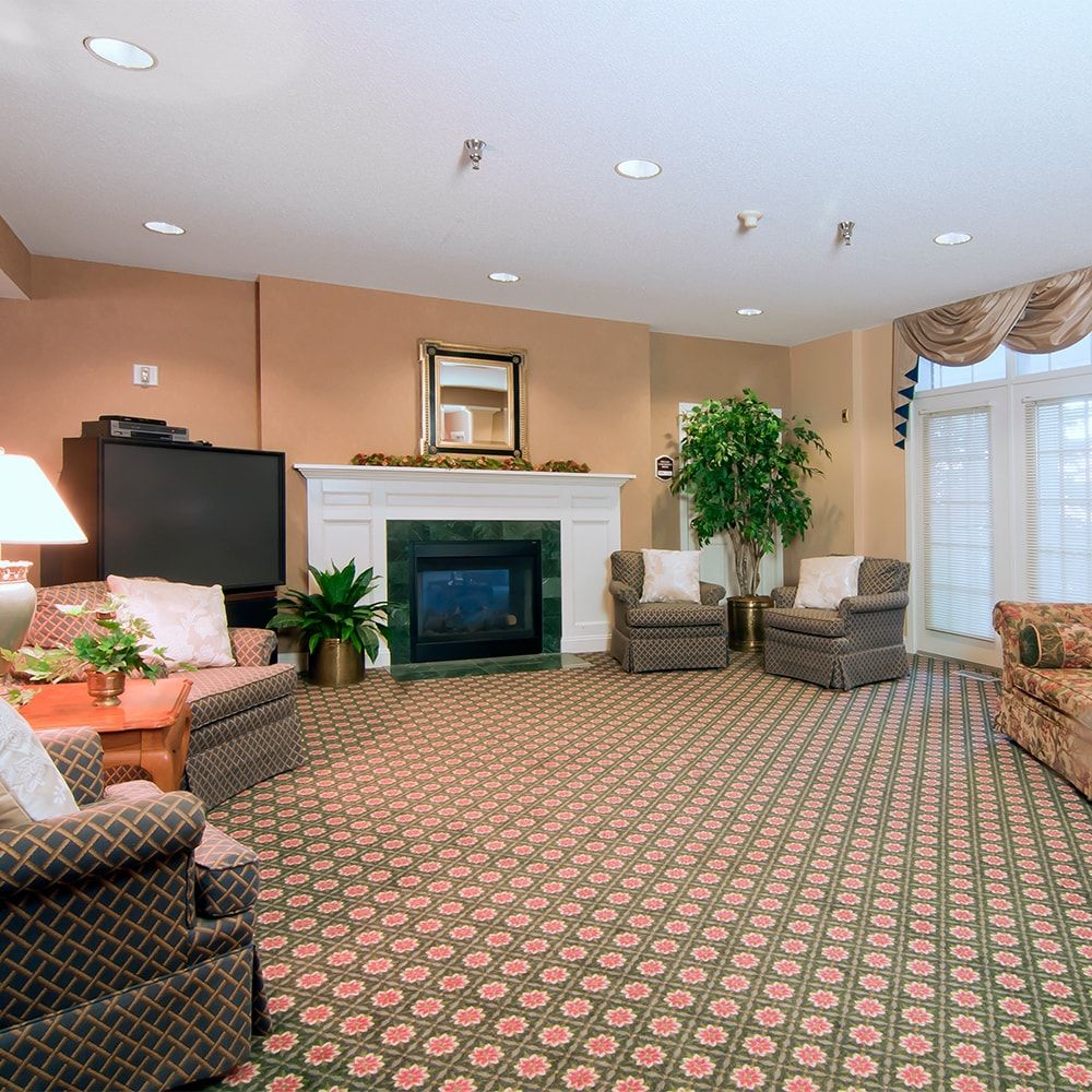 A cozy living room with a fireplace, comfortable seating, and a patterned carpet.