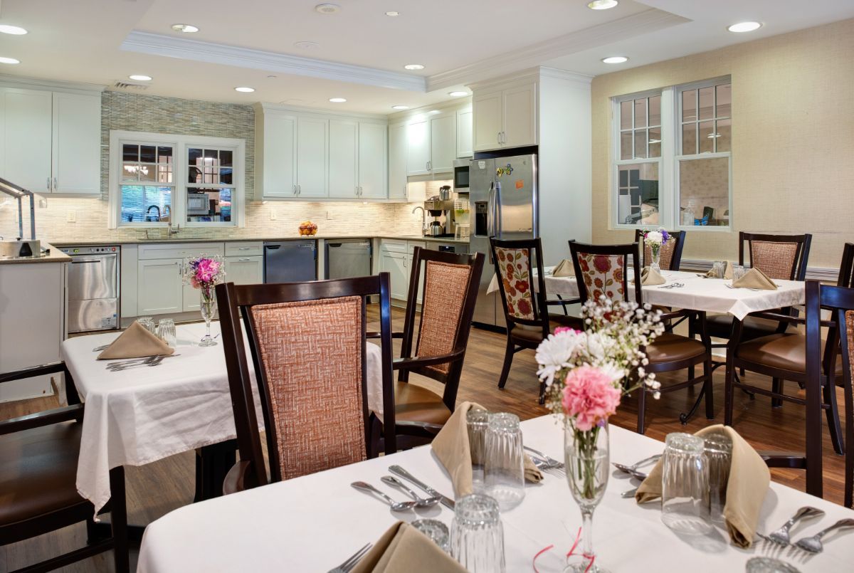 A cozy dining area with neatly arranged tables, chairs, and floral decorations.