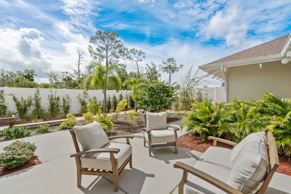A sunny backyard patio with comfortable seating and lush garden surroundings.