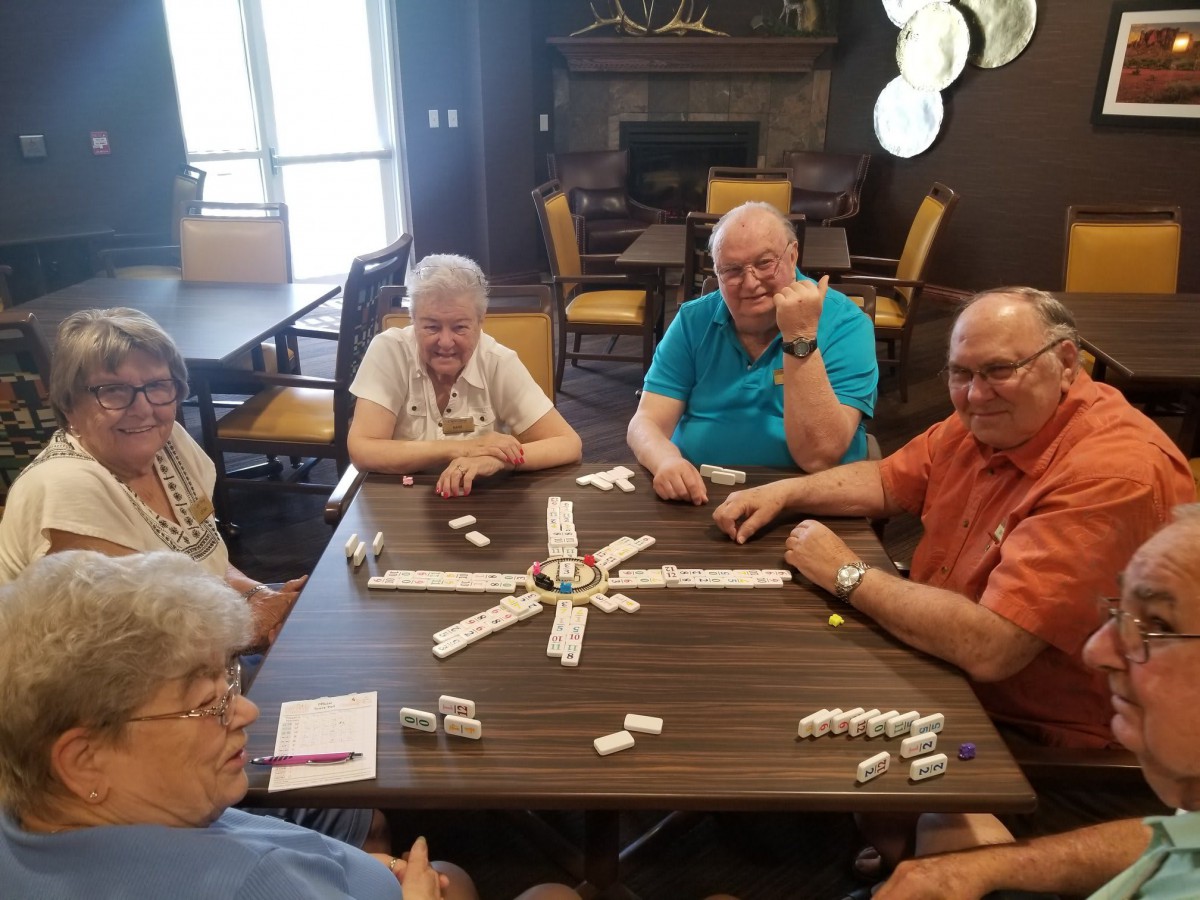 A group of seniors playing dominoes together indoors.