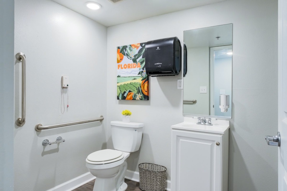 A modern bathroom with a toilet, sink, and paper towel dispenser.