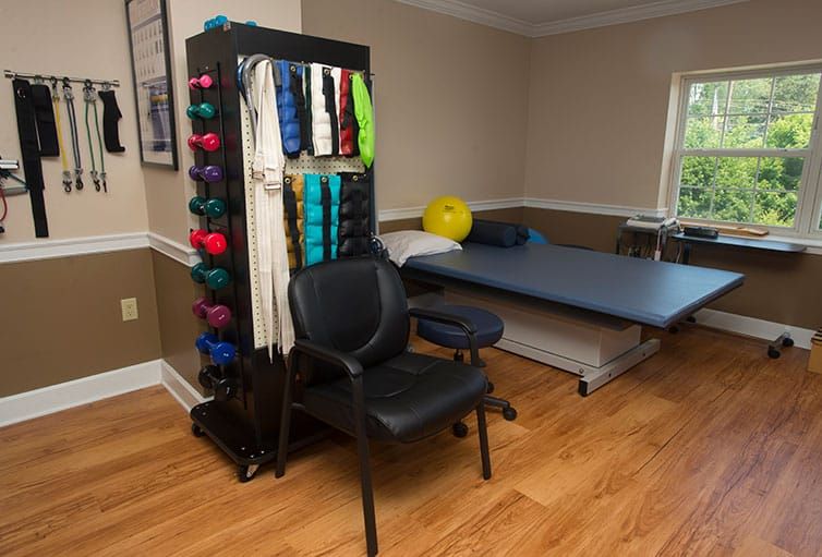 A physical therapy room featuring various exercise equipment and a massage table.