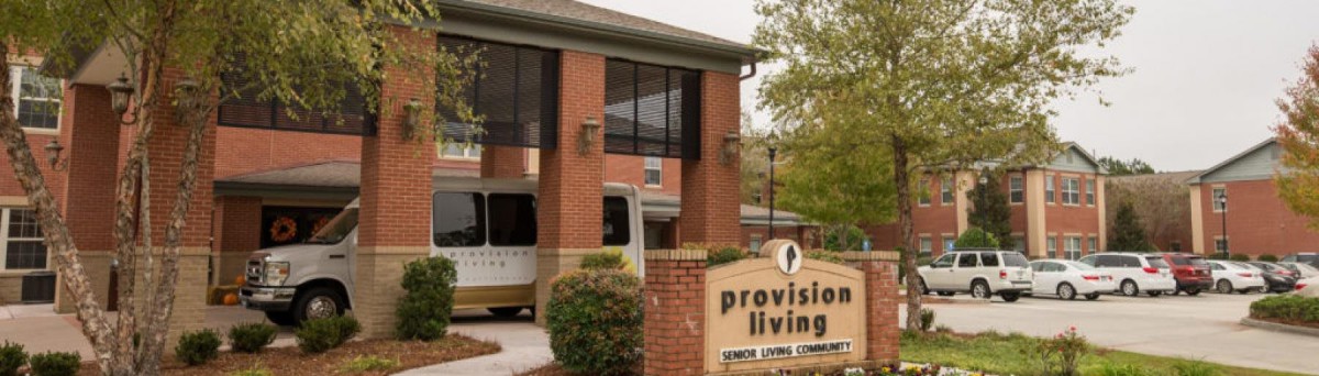 Entrance of an assisted living community with clear signage and a parked vehicle.