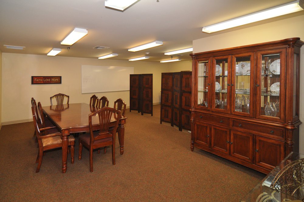 A conference room with a large wooden meeting table and chairs, surrounded by cabinets and shelves.