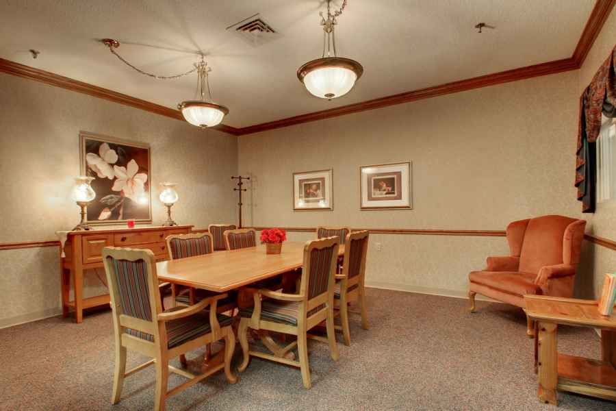 A conference room with a large wooden table, surrounded by chairs, and lit by chandeliers.