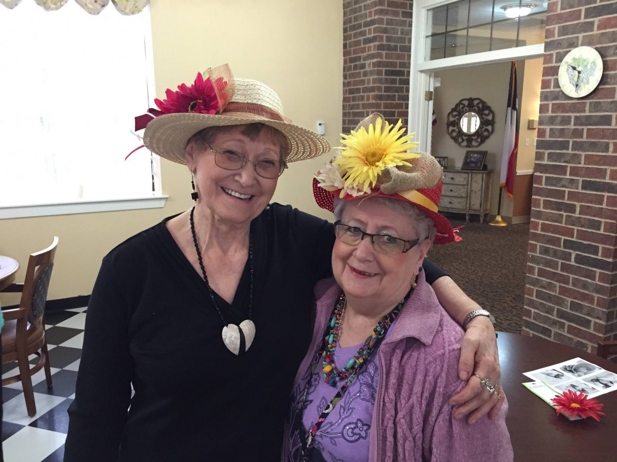 Two women wearing festive hats and smiling indoors.