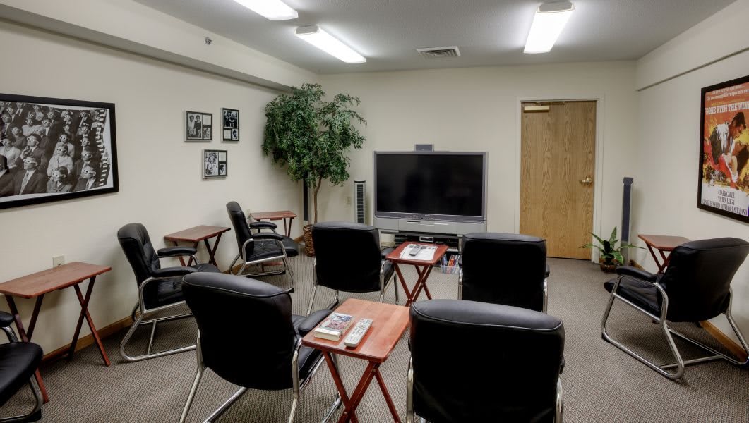 A small meeting room equipped with chairs, a television, and tables.