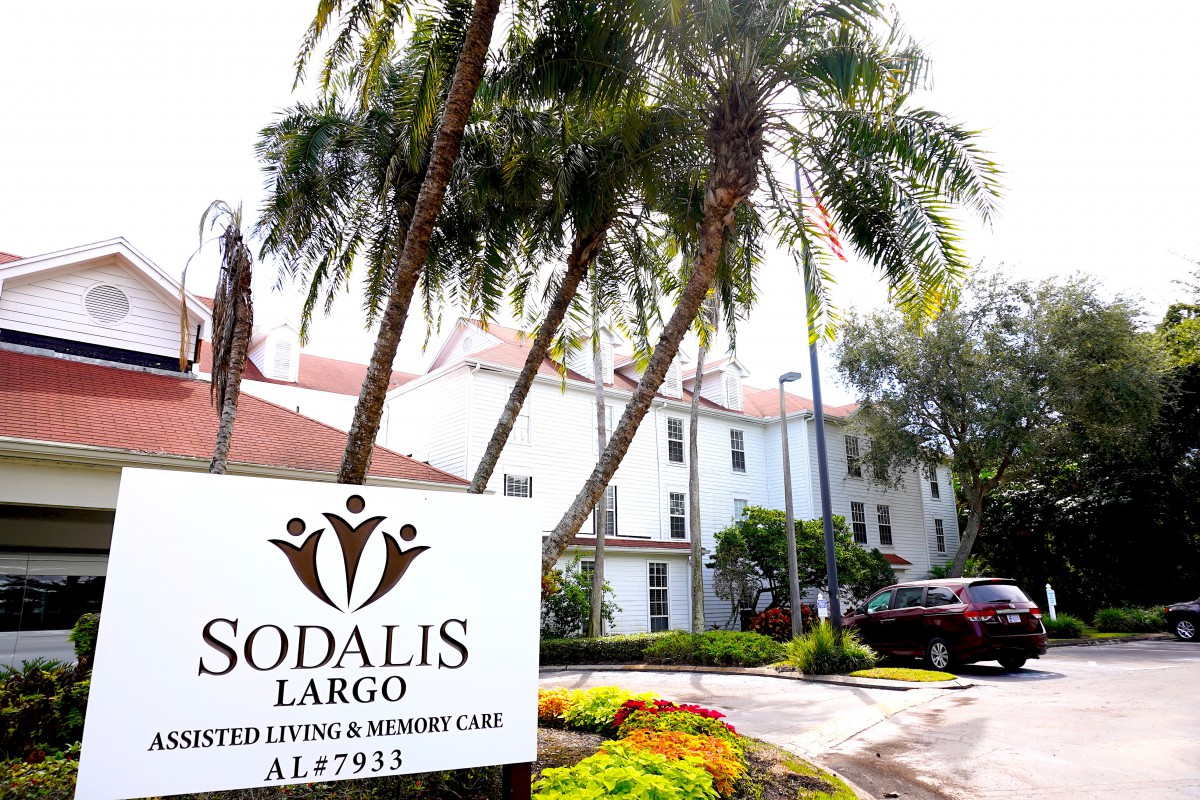 A view of the Sodalis Largo Assisted Living and Memory Care facility surrounded by palm trees.