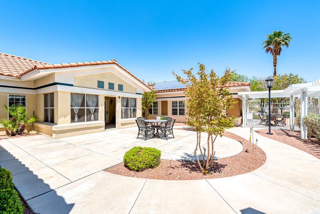 A sunny backyard with a patio and outdoor seating surrounded by simple landscaping.