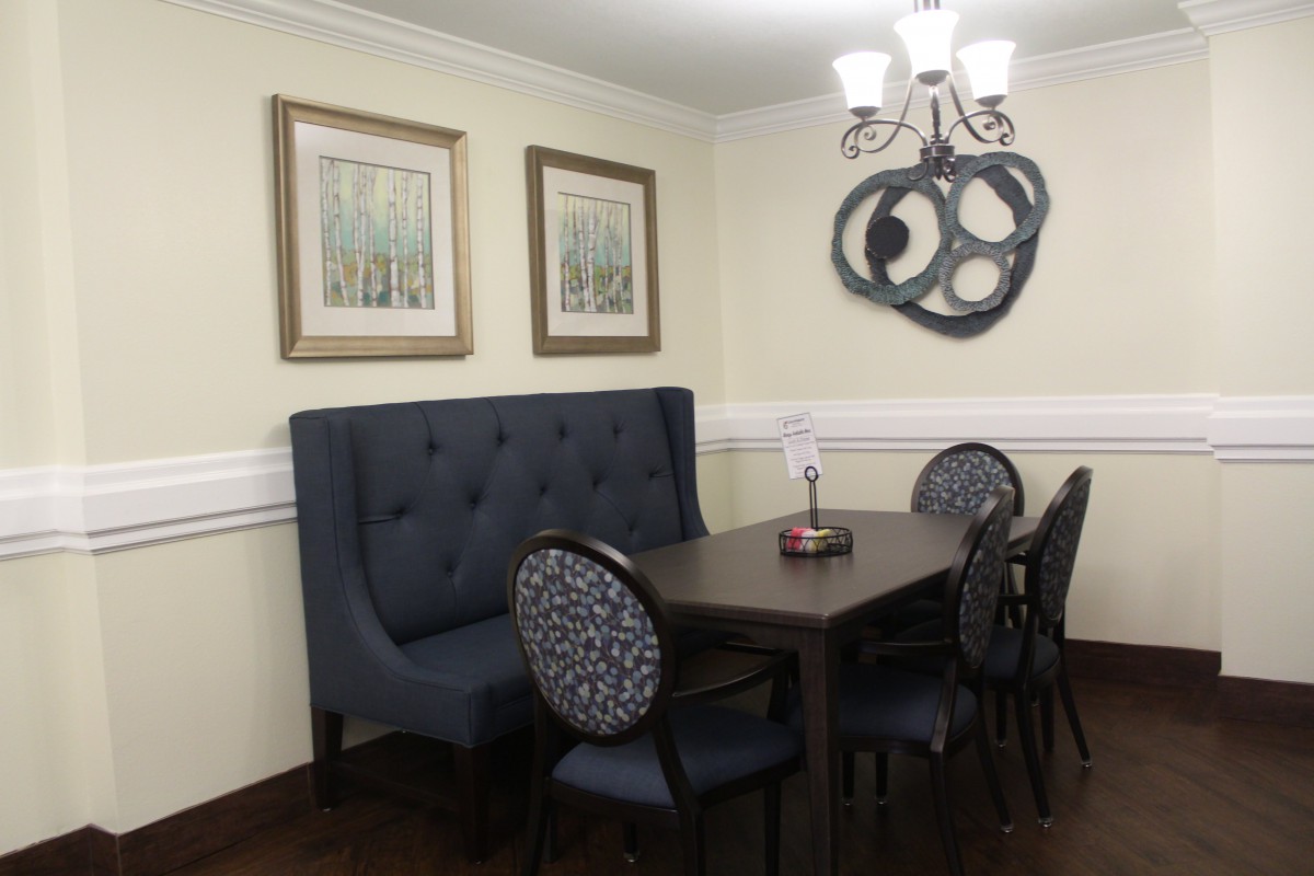 A cozy dining room with a tufted booth, elegant chairs, and modern wall art.