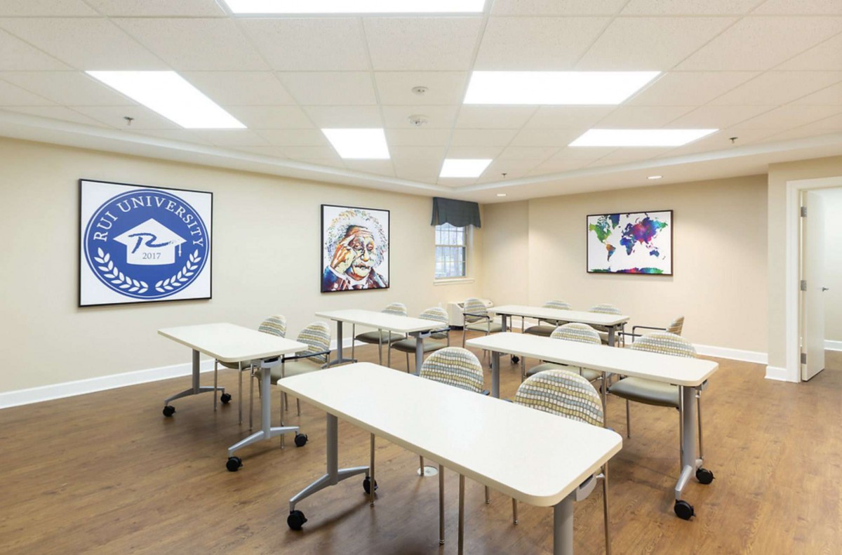 A modern classroom with neatly arranged tables and chairs, adorned with wall posters in a well-lit environment.