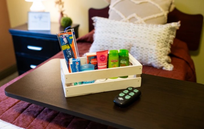 A cozy bedroom scene featuring a wooden box filled with toiletries and a remote control on the table.