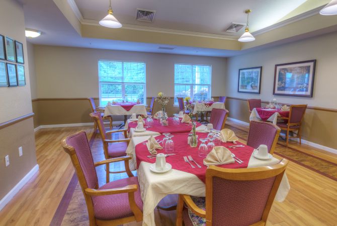 A well-arranged dining room with tables set for a meal, featuring red tablecloths and neatly folded napkins.