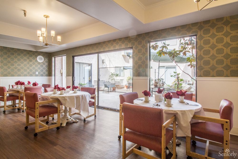 A well-lit dining room with elegantly set tables and large windows.