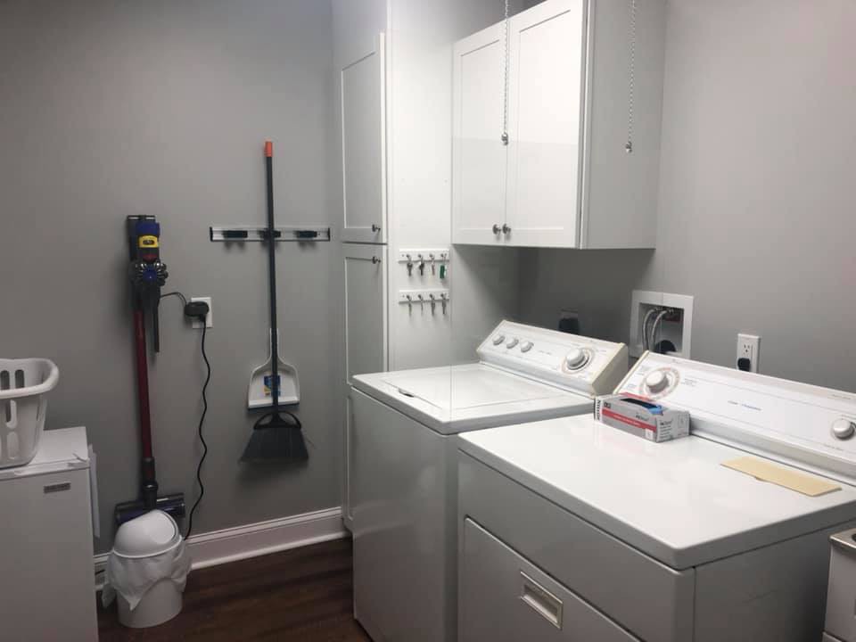 A tidy laundry room with a washing machine, dryer, and cleaning supplies organized on the wall.