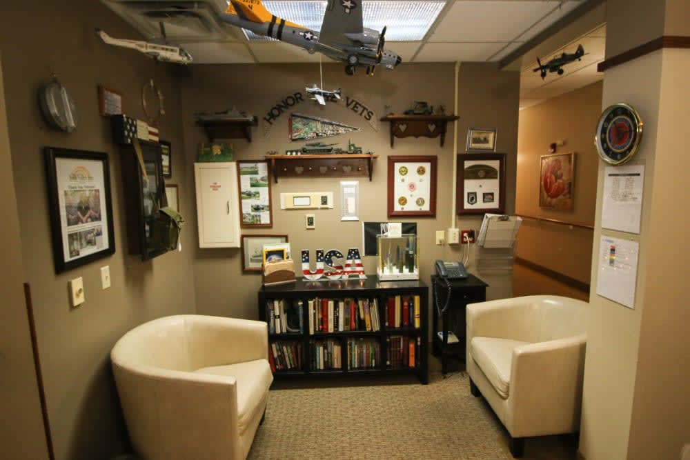 A cozy office space featuring a bookshelf, model airplanes, and comfortable chairs.