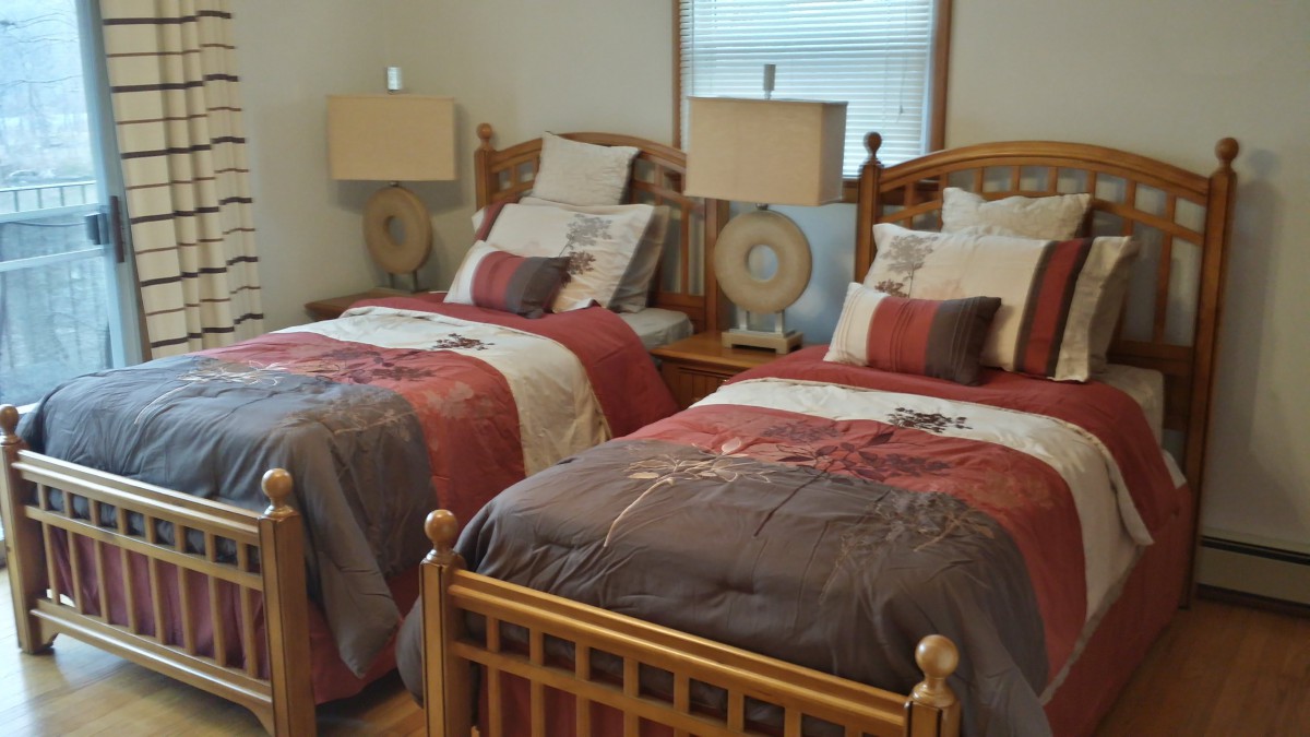 A cozy bedroom with two twin beds featuring colorful bedding and matching lamps.