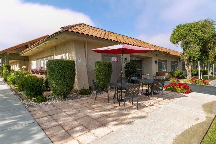 A sunny patio with outdoor seating and an umbrella beside a building.