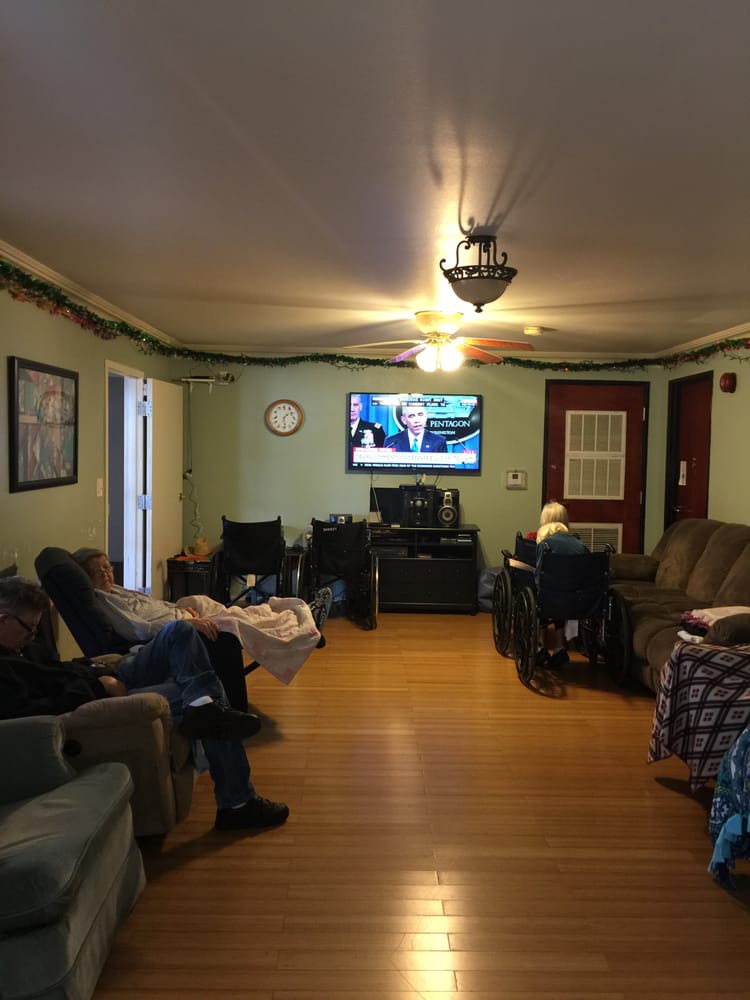 A living room with people seated and watching television.