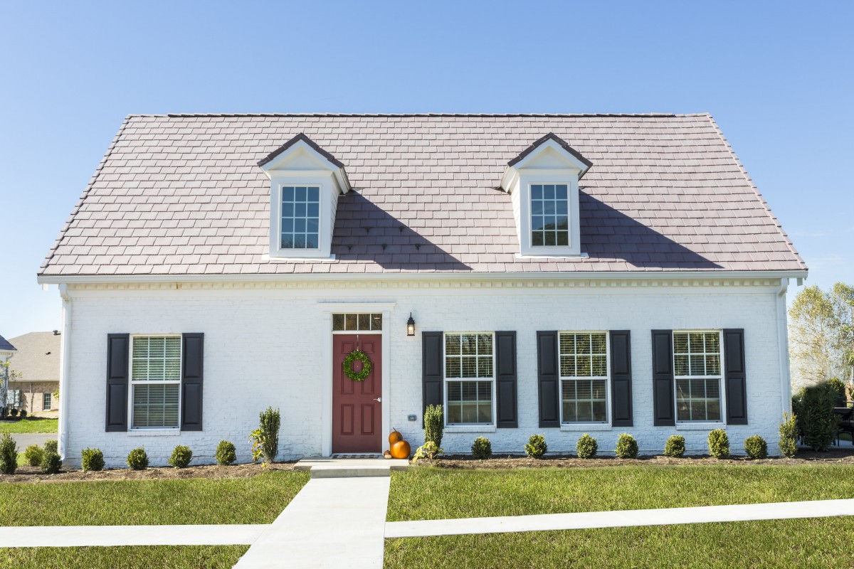 A charming suburban house with a red door and dormer windows.