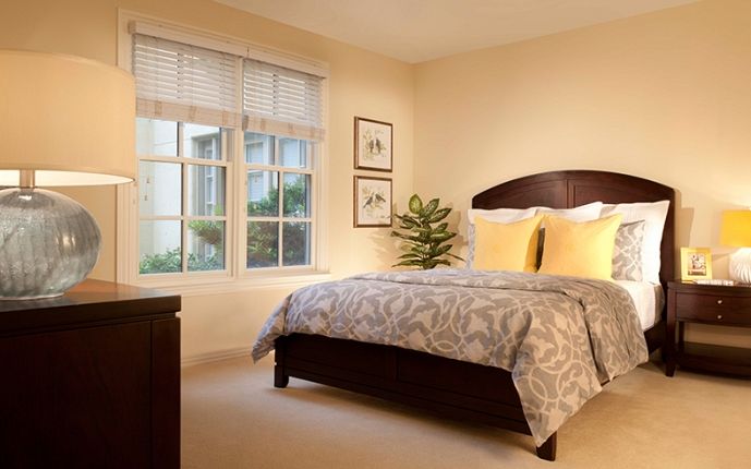 A cozy bedroom with a neatly made bed, large window, and decorative elements.