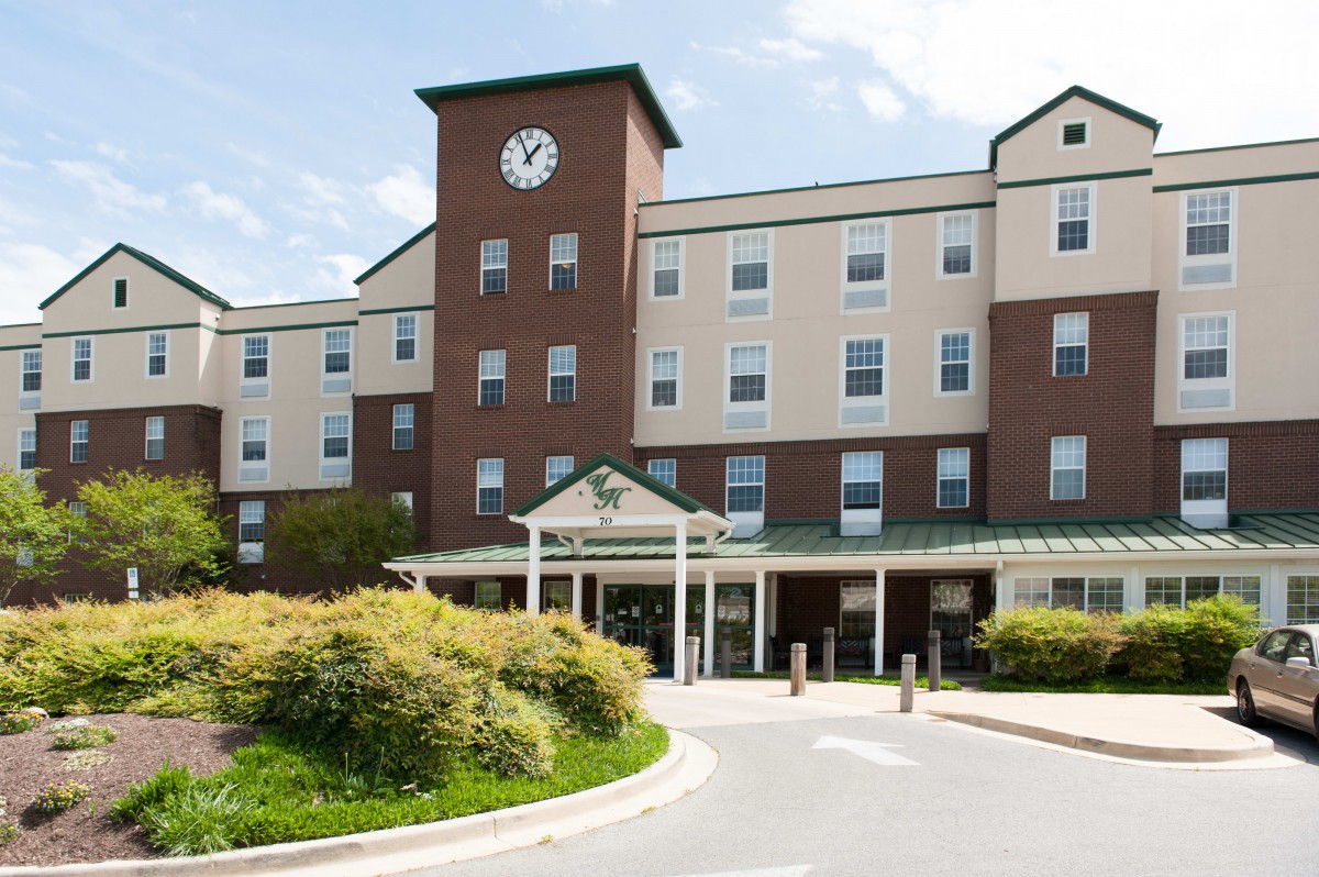 A multi-story building with a clock tower and landscaped entrance.
