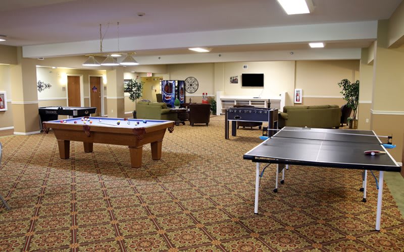 A spacious game room featuring a pool table, ping pong table, and various seating areas.