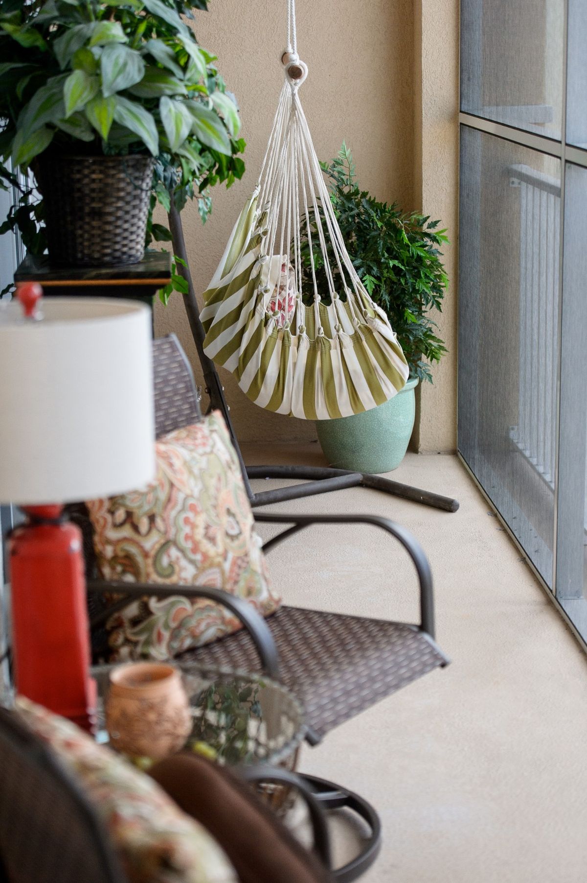 A cozy patio setting with wicker chairs, a hammock, and potted plants.