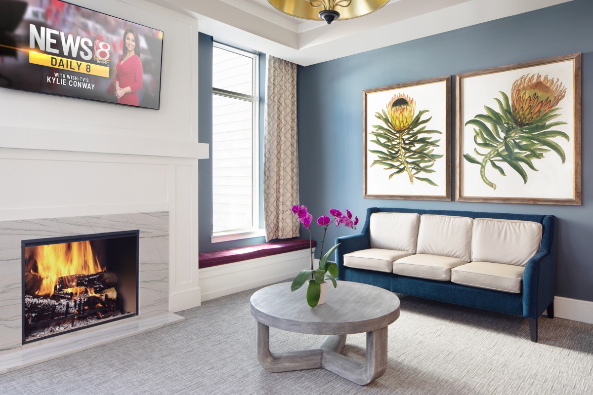 A modern living room featuring a sofa, coffee table, fireplace, and elegant artwork.
