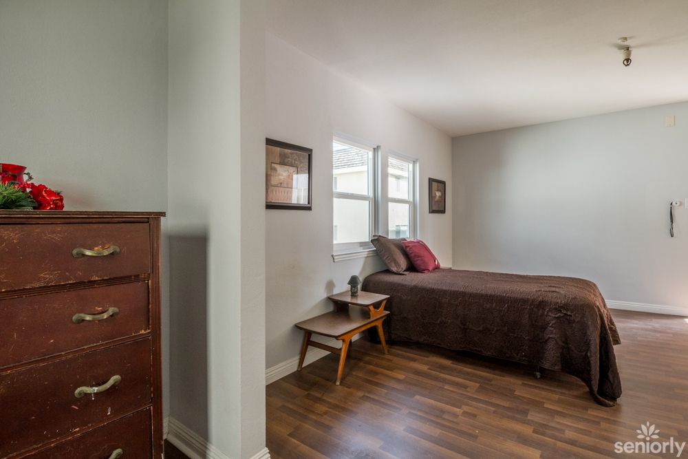 A minimalist bedroom with wooden flooring and simple furnishings.