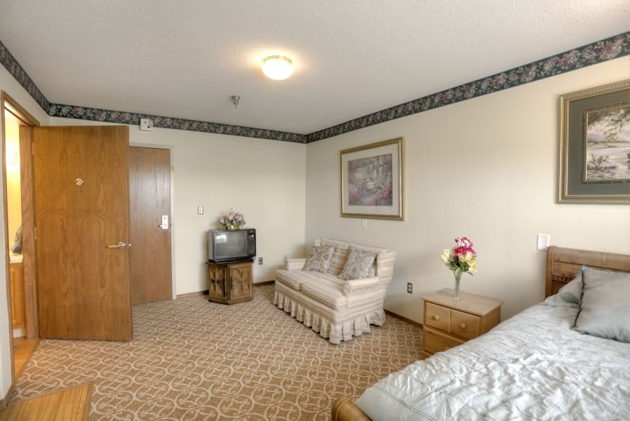 A cozy living room with a sofa, television, and floral decor.