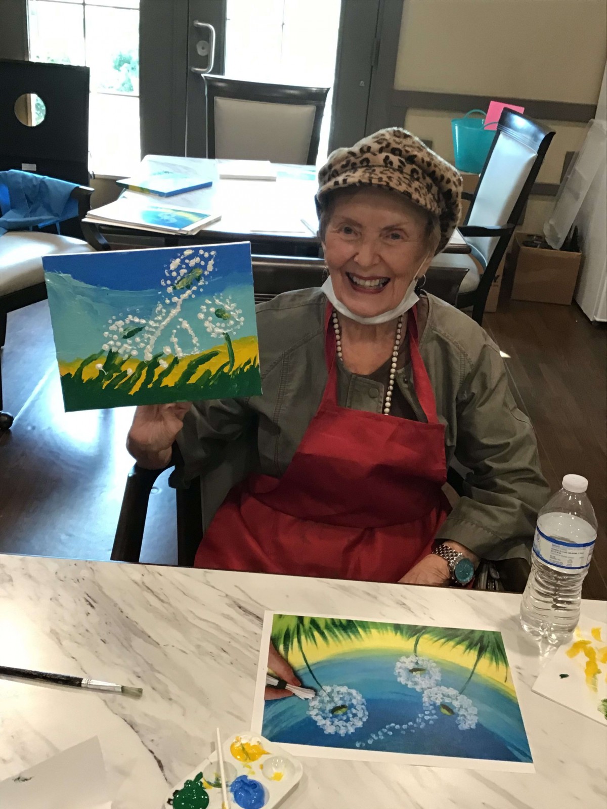 An elderly person happily displaying a painting during an art activity.