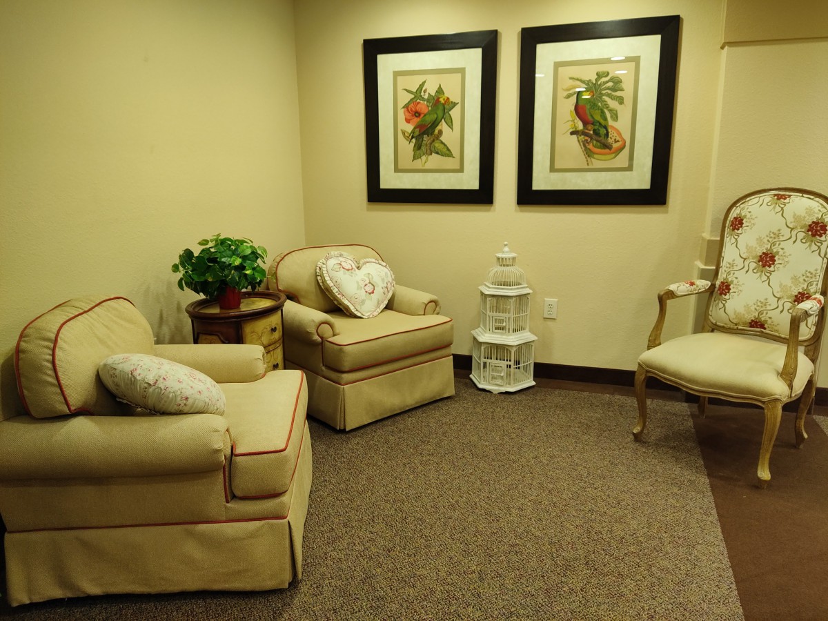 A cozy living room with comfortable chairs, art on the walls, and warm lighting.