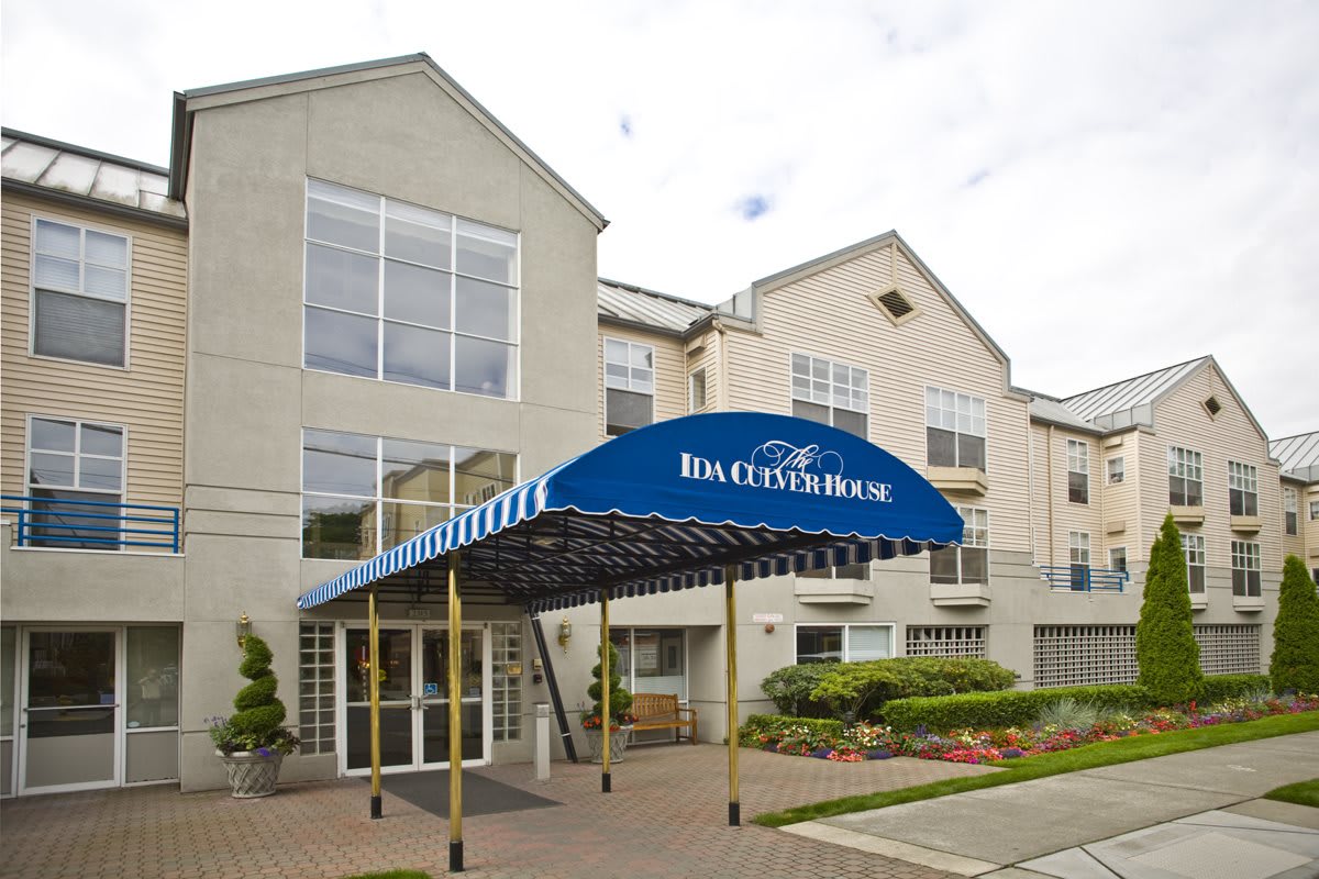 The entrance of a hotel with a blue awning and modern architecture.