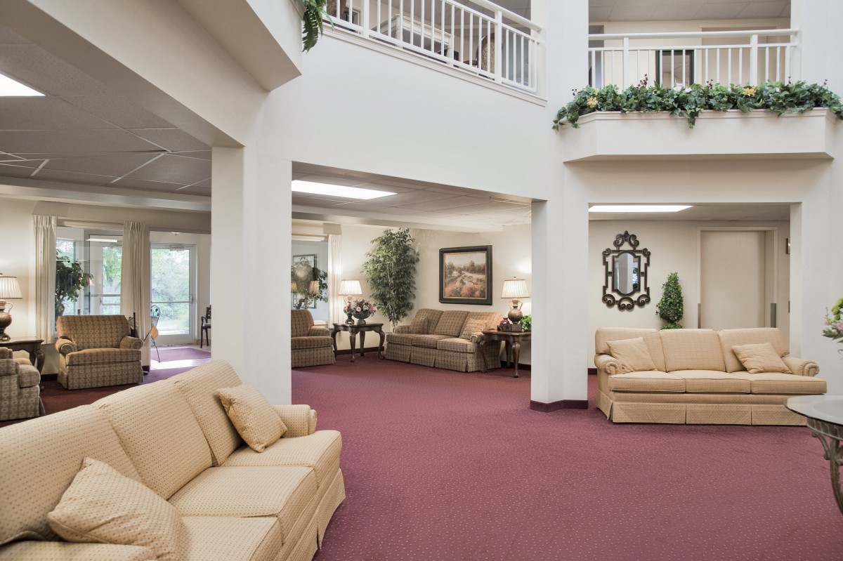 A spacious lobby area with sofas, decorative plants, artwork, and a mirror.