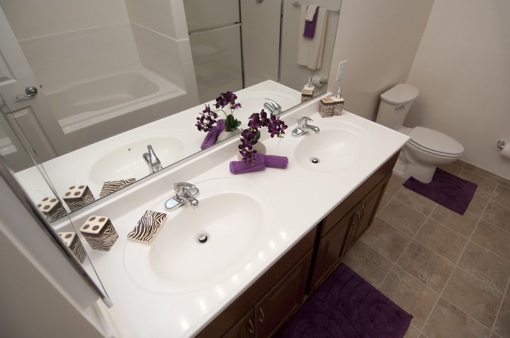 A modern bathroom with a double sink, decorated with flowers and purple accents.