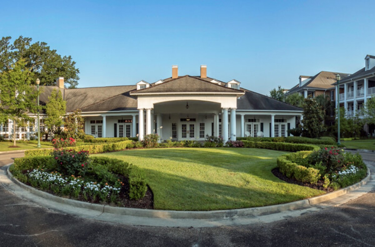 A large, elegant building with a circular driveway and manicured gardens.