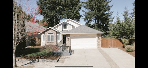 A charming single-story house with a manicured driveway and surrounding greenery.
