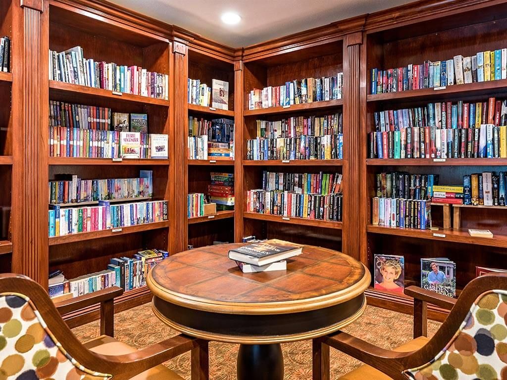 A cozy library corner with wooden bookshelves and a round table.