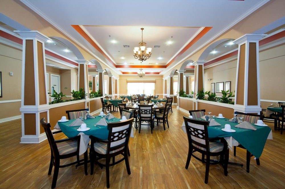 An elegant restaurant dining area with neatly arranged tables and chairs under a decorative ceiling.