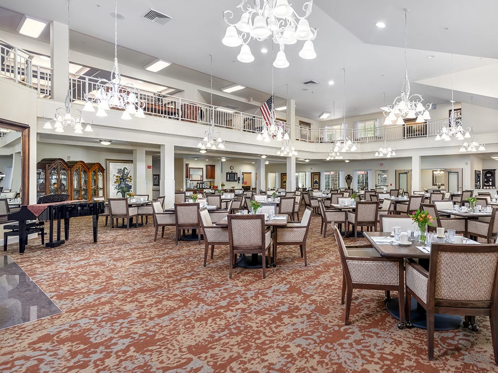 A spacious and elegantly designed dining area with multiple tables and chandeliers.