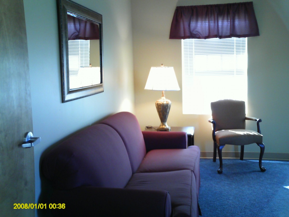 A cozy living room with a sofa, chair, and lamp by the window.