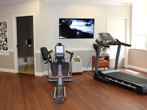 A well-equipped fitness room featuring a treadmill and a stationary bike, with a television mounted on the wall.