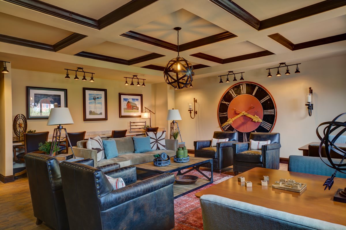A stylish living room featuring comfortable seating, a large wall clock, and elegant decor.