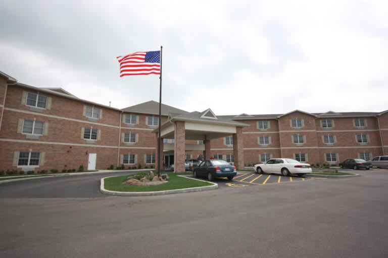 A hotel with a parking lot and an American flag flying outside.