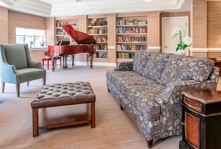 A cozy living room with a piano and bookshelves.