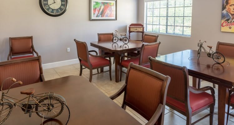 A dining room with a wooden table, upholstered chairs, and artwork on the wall.