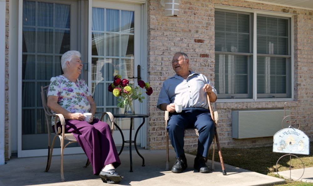 Two seniors enjoying a conversation on a sunny patio.