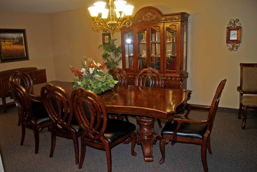A beautifully arranged dining room featuring an elegant wooden table and chairs, complemented by a stylish chandelier and a display cabinet.