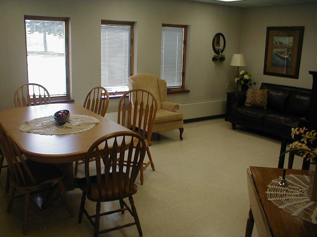 A cozy living room with wooden furniture and multiple windows.